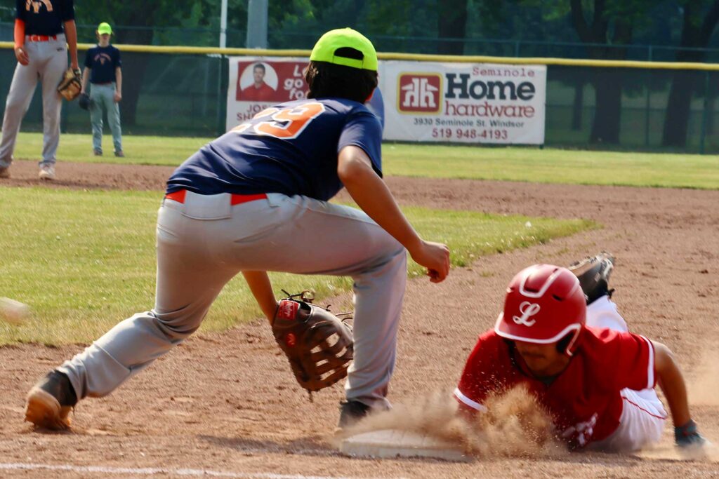 Runner dives back into the base after a throw over.